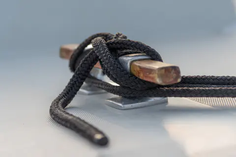 Mooring rope tied around a cleat on a boat deck