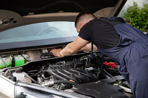 Mechanic's hands working on parts in a car engine bay