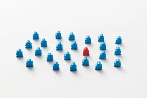 Red board game piece among blue game pieces
