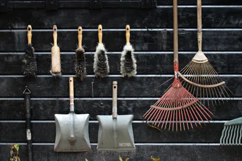 Garden tools hanging on a wooden shed wall
