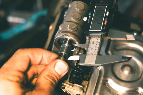 Mechanic measuring a metal part with a digital caliper