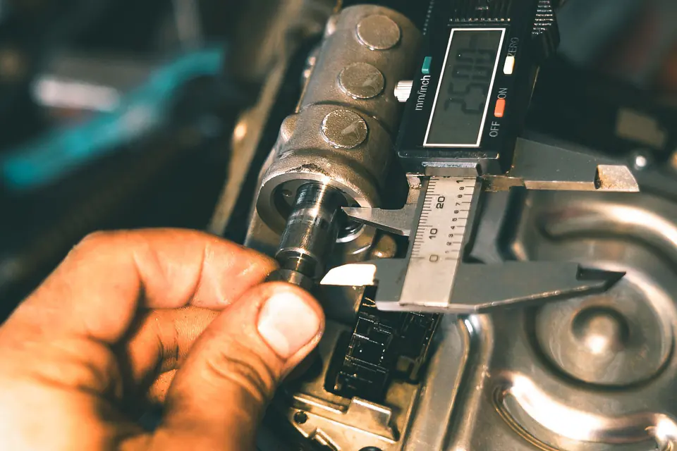 Mechanic measuring a metal part with a digital caliper