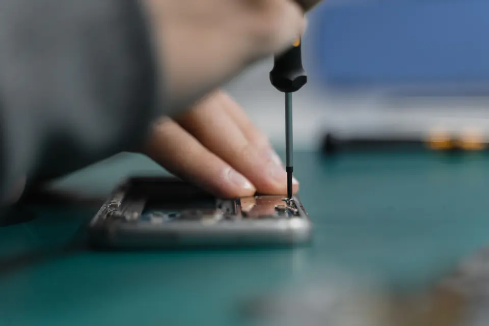 Hand repairing a smartphone with a small screwdriver